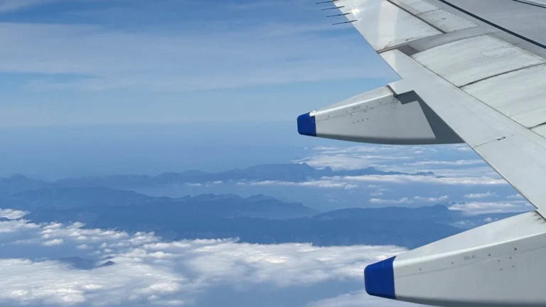 Asa de avião recortada contra nuvens e céu azul