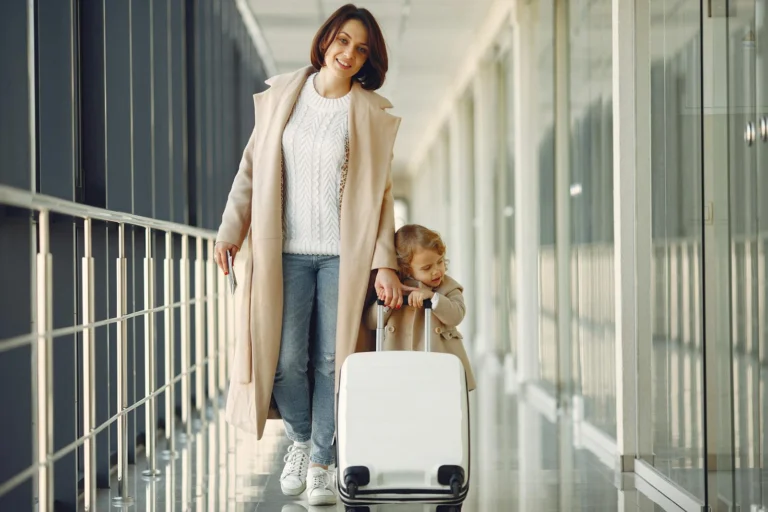 Mae e filha caminhando com mala em aeroporto