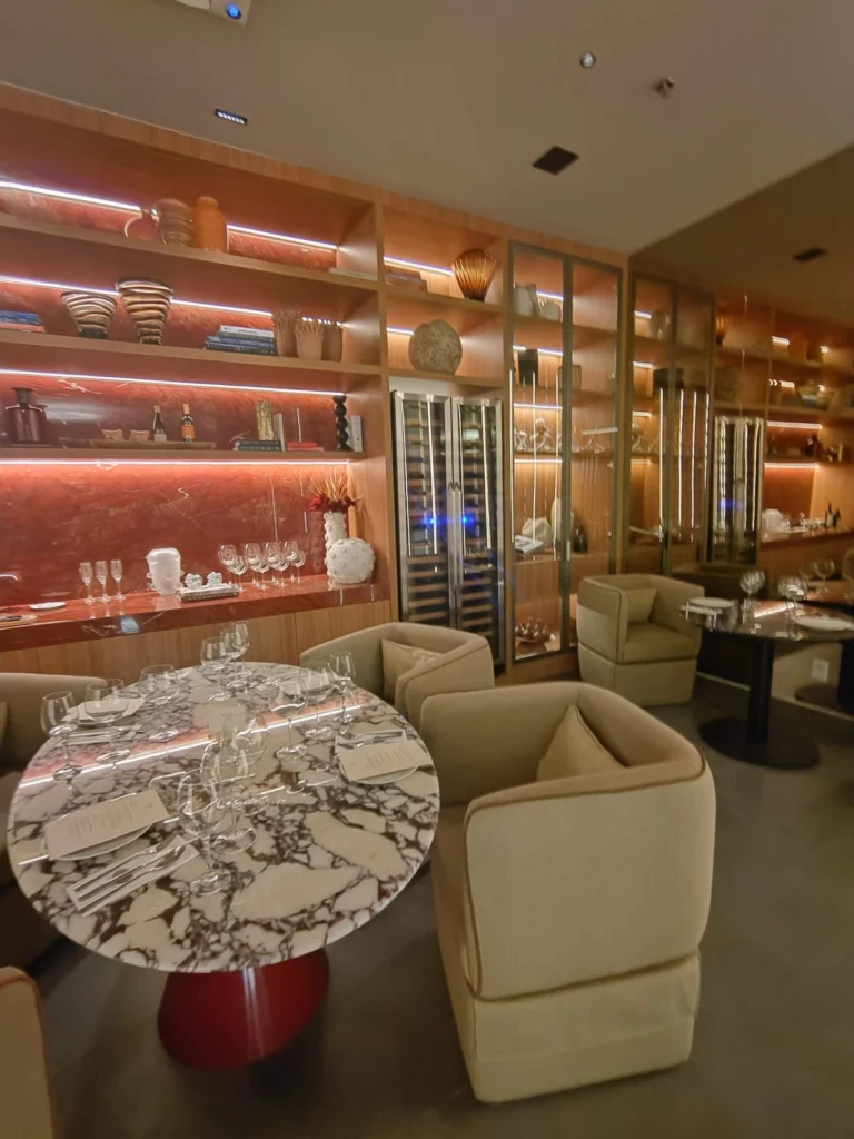 Sala de degustação de vinhos da Taste of Priceless, com mesa de mármore, poltronas e adega climatizada