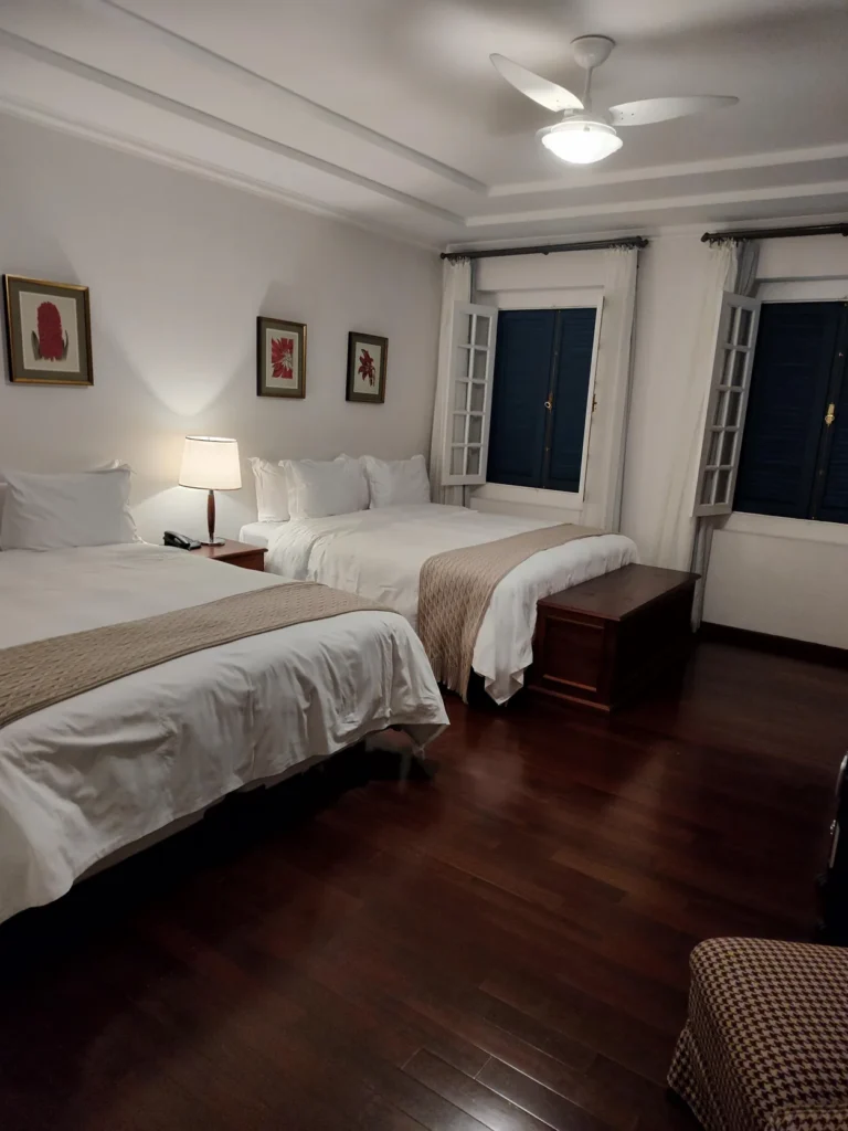 Quarto amplo da Fazenda Dona Carolina com piso de madeira e duas camas