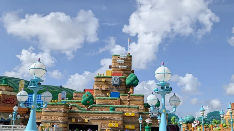 Montanha cenográfica da Super Nintendo World no Universal Epic Universe, com os dois lampiões azuis e a loja Mario Motors à esquerda. Foto própria, 2026.
