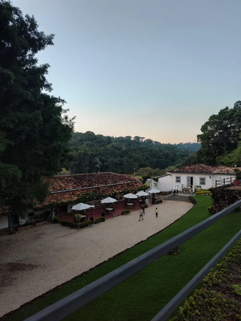 Área externa de jantar da Fazenda Dona Carolina ao entardecer, com serra ao fundo. Foto própria, 2026.