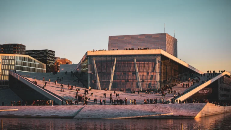 A Ópera de Oslo ao entardecer, com pessoas no telhado inclinado