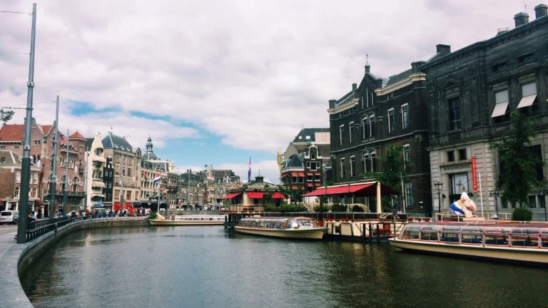 Canal de Amsterdã com barcos de passeio e o casario histórico holandês às margens