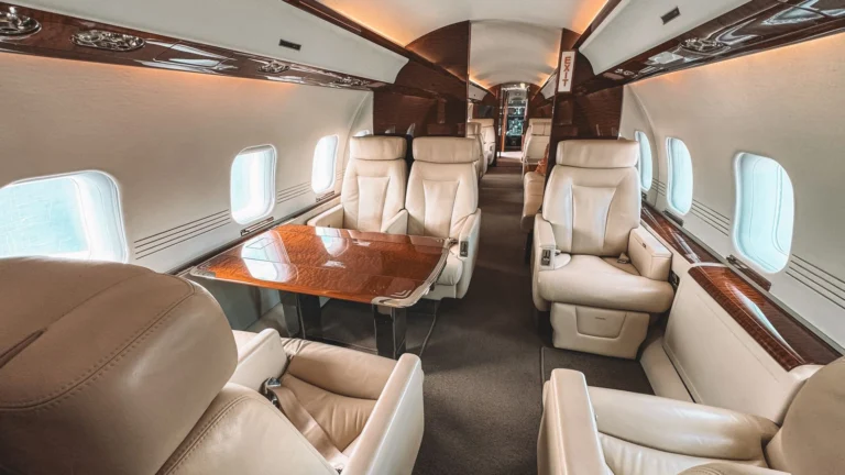 Cabine de avião de luxo com poltronas de couro creme e acabamento em madeira, no estilo de primeira classe.
