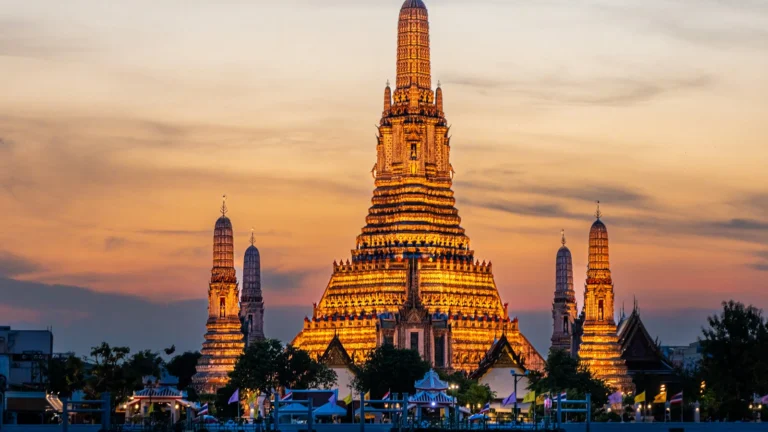 O templo Wat Arun iluminado ao pôr do sol, à beira do rio Chao Phraya, em Bangkok