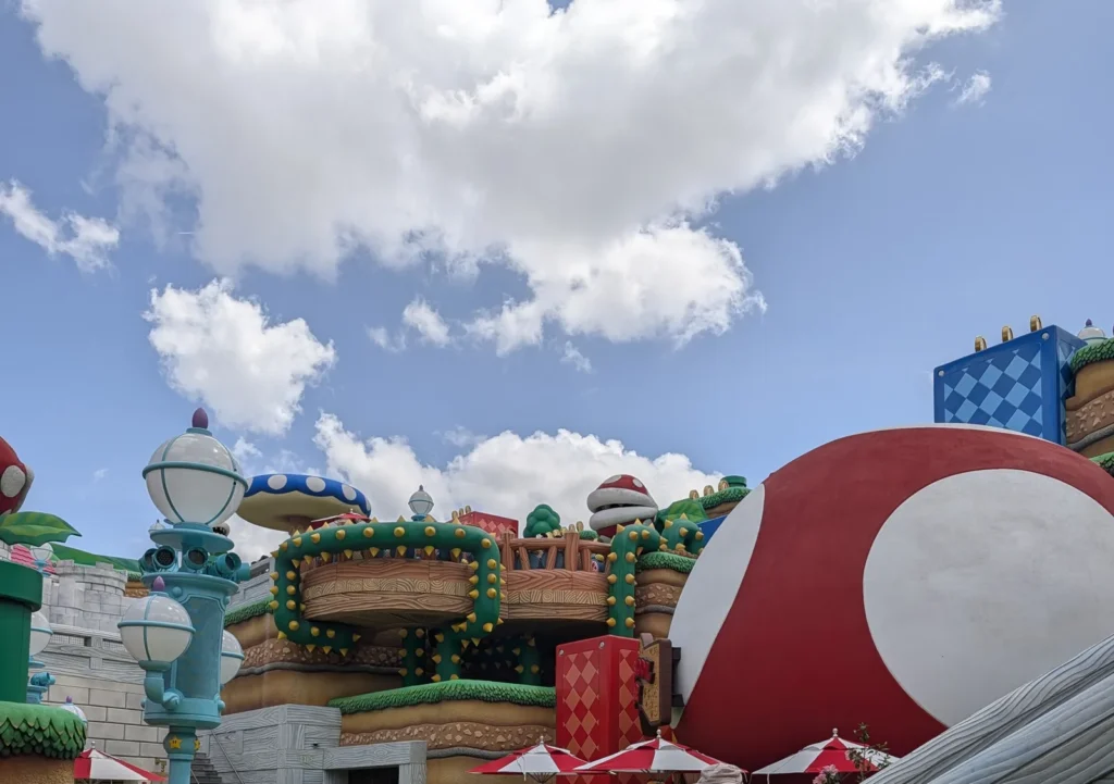 Skyline da Super Nintendo World no Epic Universe com o cogumelo gigante vermelho e branco do Toadstool Cafe. Foto própria, abril de 2026.