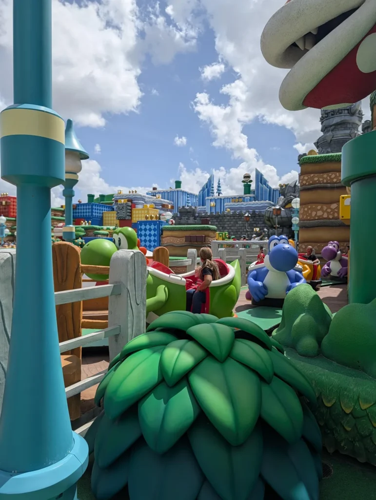 Veículos de Yoshi verdes, azuis e roxos no trecho externo da Yoshi's Adventure, Super Nintendo World, Epic Universe. Foto própria, abril de 2026.