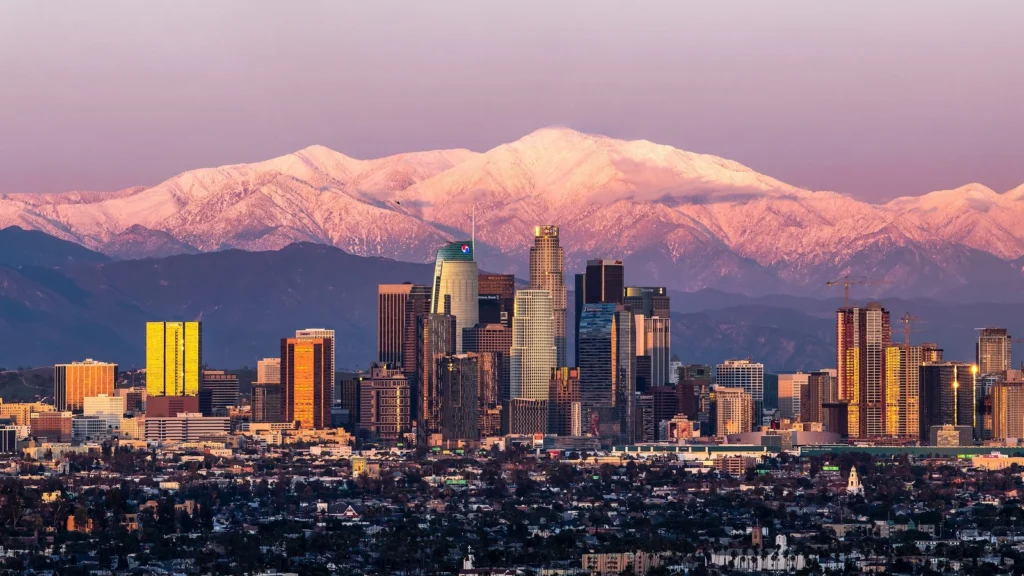 Prédios do centro de Los Angeles com o Mount Baldy coberto de neve ao fundo, ao entardecer