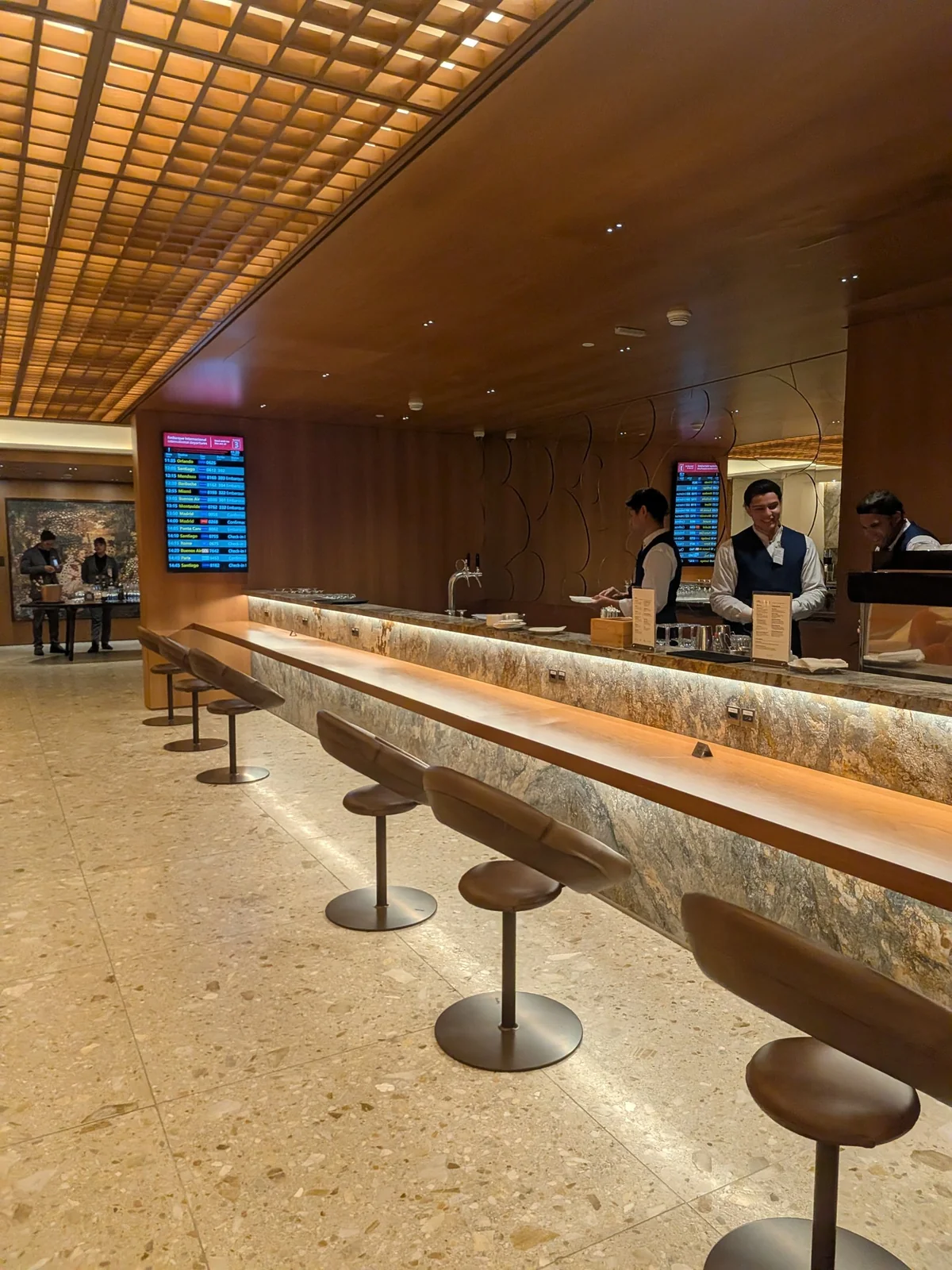 Bar central da Sala VIP Pedra Preta com bancada em pedra translúcida iluminada, chopeira e atendentes uniformizados