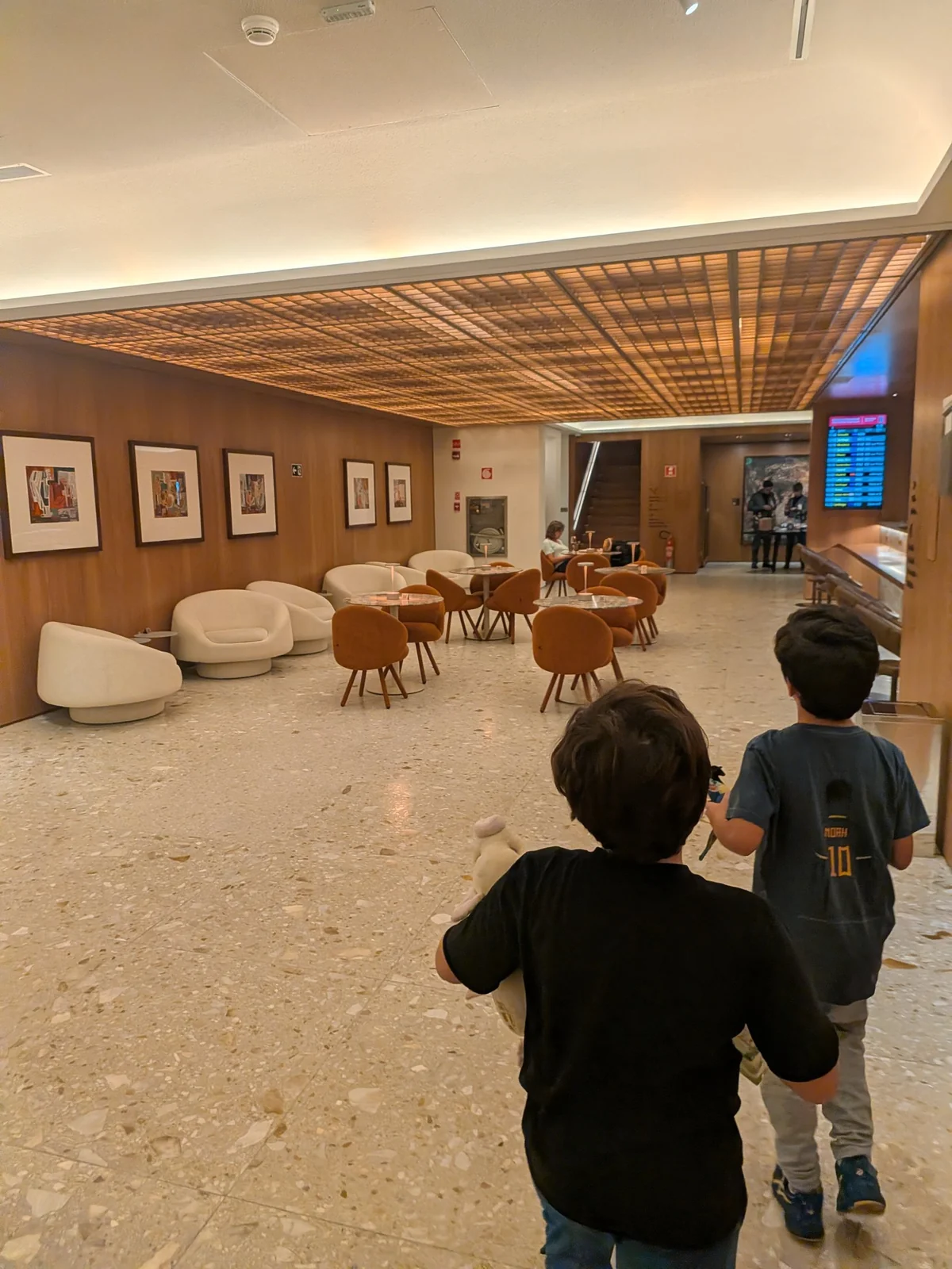 Hall principal da Sala VIP Pedra Preta do Itaú Personnalité no Terminal 3 de Guarulhos com piso de granito e galeria de arte