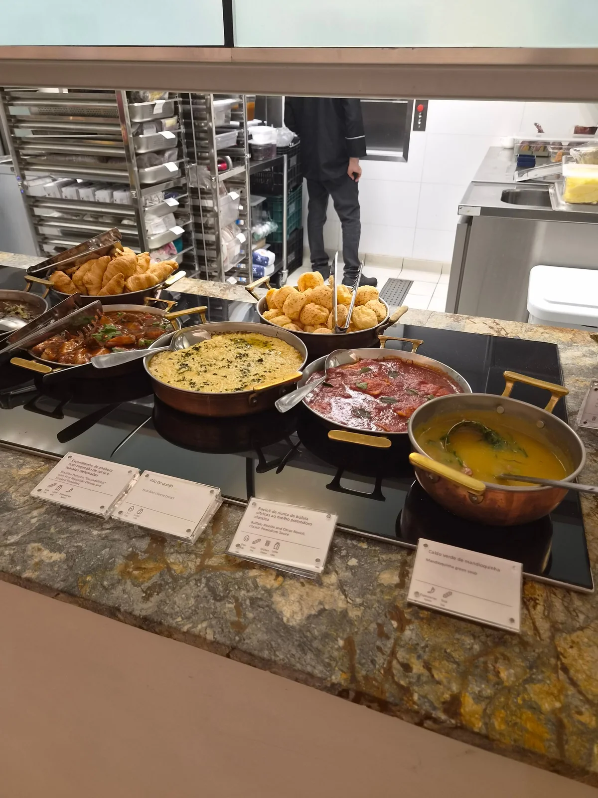 Seleção de pratos quentes em panelas de cobre: ravioli de ricota de búfala ao pomodoro, caldo verde de mandioquinha e pão de queijo